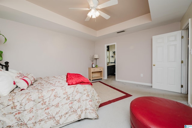 carpeted bedroom with ceiling fan, connected bathroom, and a raised ceiling