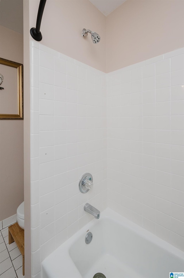 bathroom featuring tile patterned flooring, tiled shower / bath, and toilet