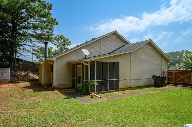 rear view of property featuring a yard and a sunroom