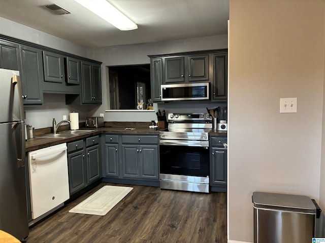 kitchen featuring sink, dark wood-type flooring, appliances with stainless steel finishes, gray cabinetry, and butcher block counters