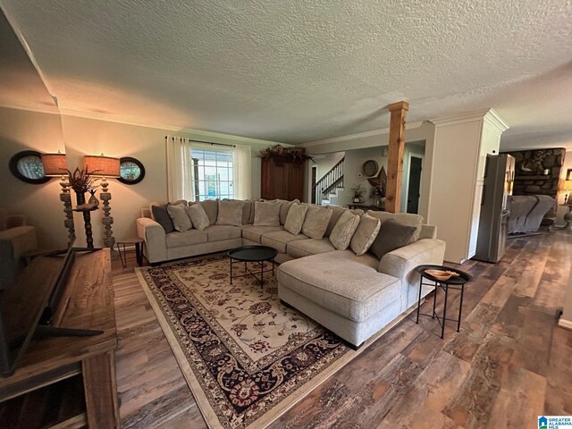 living room with dark wood-style floors, a textured ceiling, stairway, and crown molding