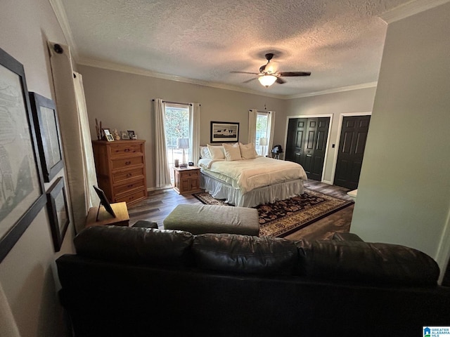 bedroom with a textured ceiling, crown molding, and multiple closets