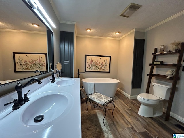 bathroom with a sink, toilet, visible vents, a freestanding tub, and wood finished floors