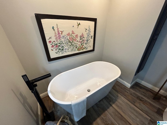 bathroom with a soaking tub, baseboards, and wood finished floors