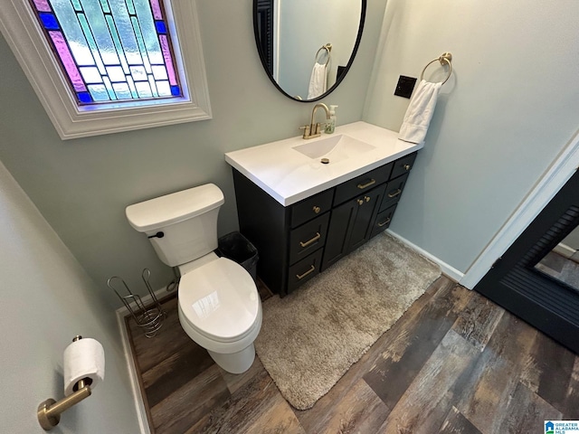 bathroom with baseboards, wood finished floors, toilet, and vanity