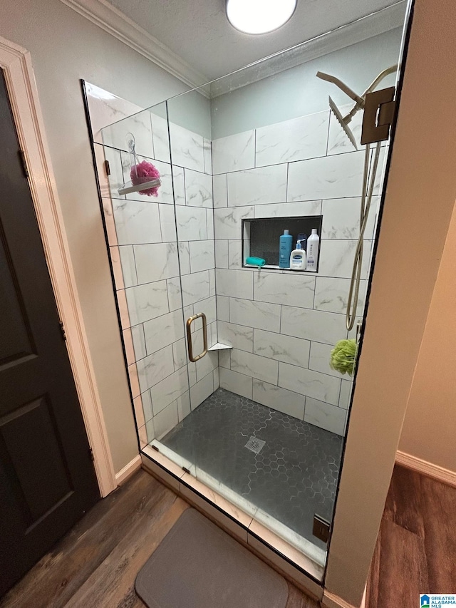 full bath featuring a shower stall, wood finished floors, crown molding, and baseboards