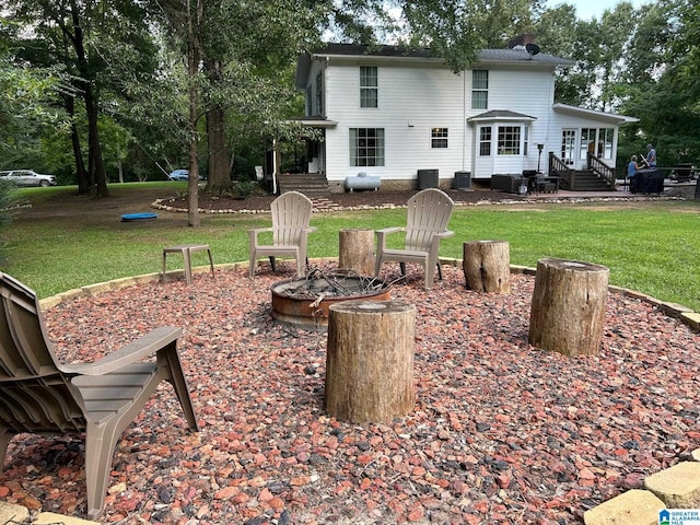 rear view of house featuring cooling unit, a yard, and an outdoor fire pit
