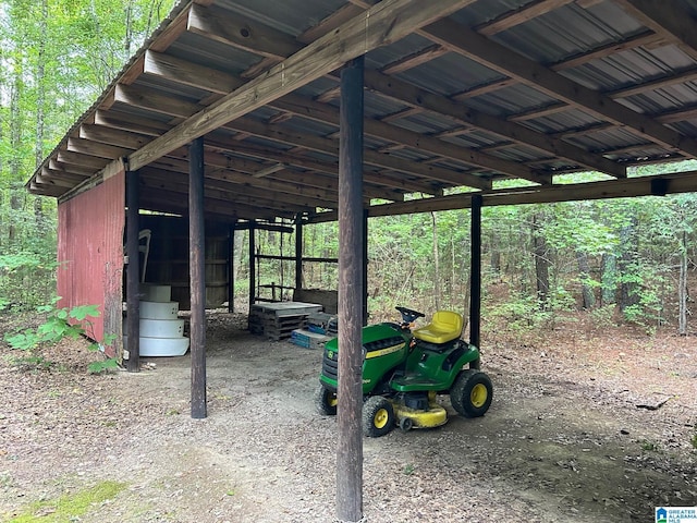 view of patio / terrace featuring a forest view, an outdoor structure, a carport, and a pole building