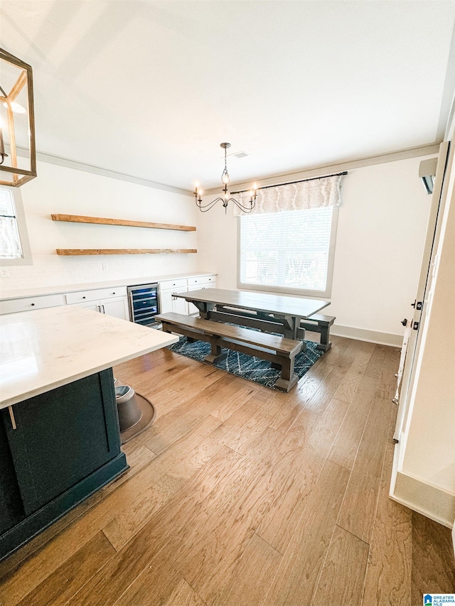 dining room featuring an inviting chandelier, beverage cooler, and light hardwood / wood-style floors