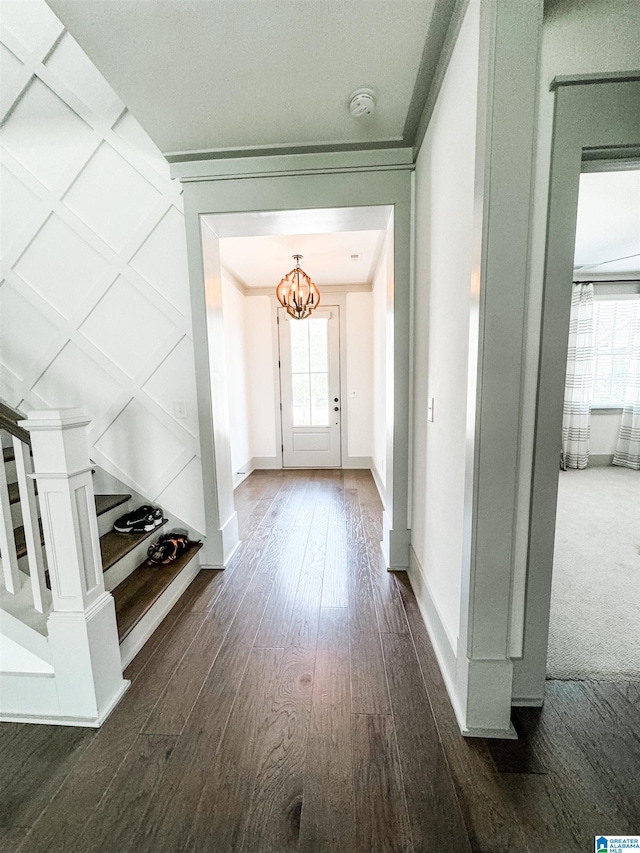 hall featuring plenty of natural light, dark wood-type flooring, and a notable chandelier