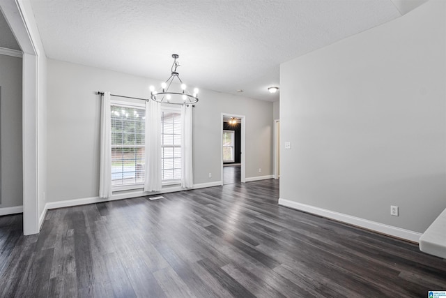 unfurnished dining area featuring an inviting chandelier, dark hardwood / wood-style floors, and a textured ceiling