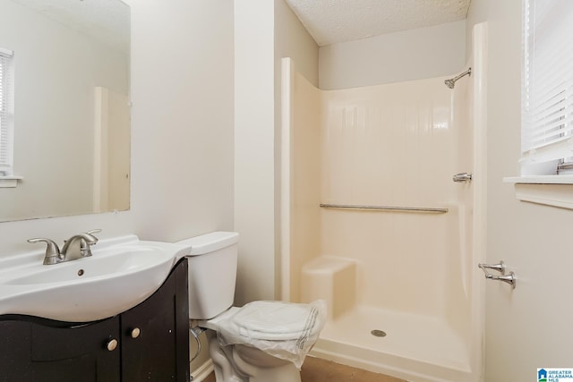 full bathroom with toilet, a textured ceiling, a shower stall, and vanity