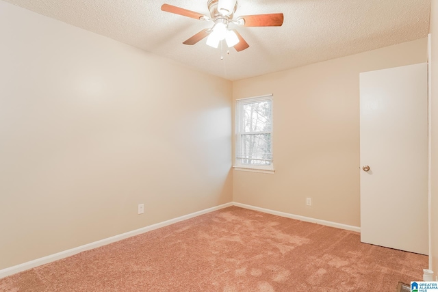 spare room featuring light carpet, a textured ceiling, a ceiling fan, and baseboards