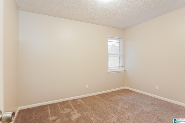 carpeted spare room with a textured ceiling and baseboards