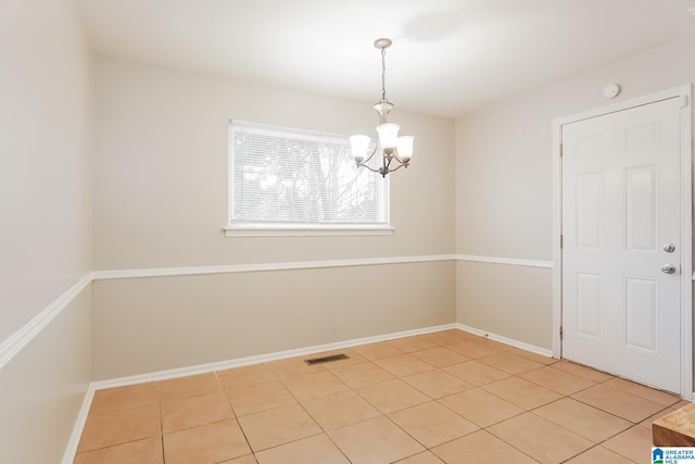 unfurnished room featuring an inviting chandelier, baseboards, light tile patterned floors, and visible vents