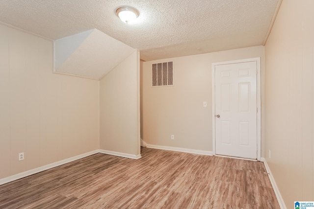 bonus room featuring lofted ceiling, light wood-type flooring, visible vents, and a textured ceiling