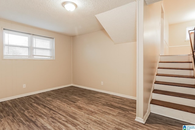 basement featuring a textured ceiling, stairway, and wood finished floors