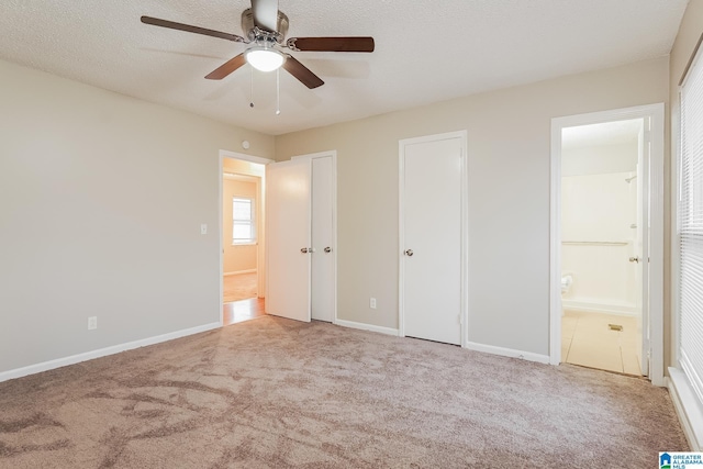 unfurnished bedroom with carpet floors, ensuite bath, baseboards, and a textured ceiling