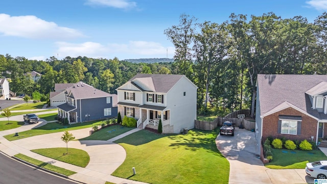 view of front of home with concrete driveway, a front lawn, fence, and a residential view