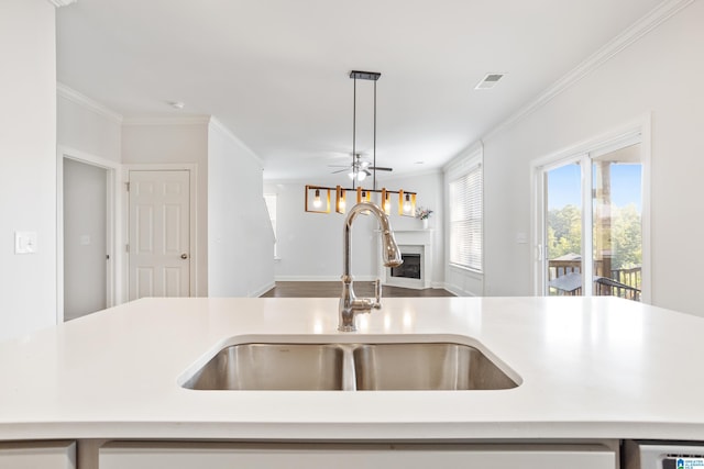 kitchen with decorative light fixtures, ceiling fan, ornamental molding, and sink