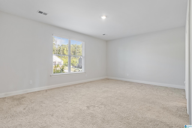 empty room with light colored carpet, visible vents, and baseboards