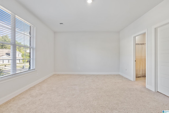 unfurnished bedroom featuring light colored carpet, connected bathroom, and baseboards