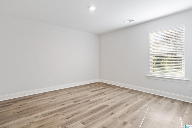 spare room featuring visible vents, light wood-style flooring, and baseboards