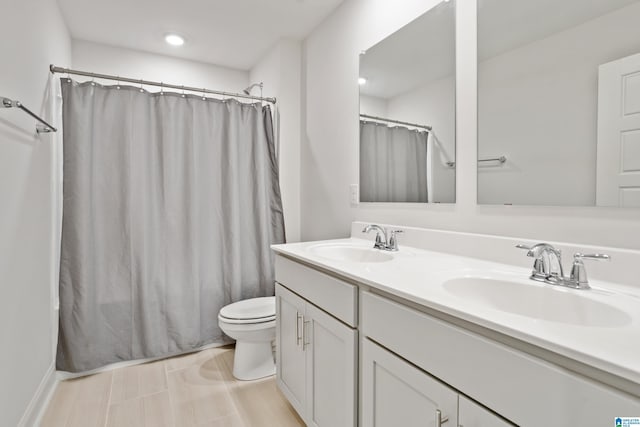 bathroom with double vanity, a sink, and toilet