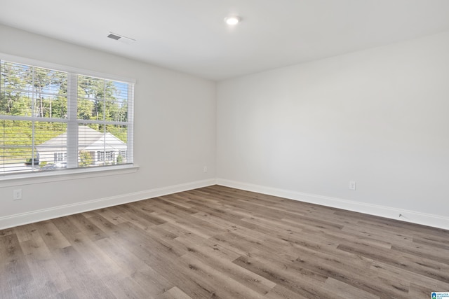 spare room featuring visible vents, baseboards, and wood finished floors