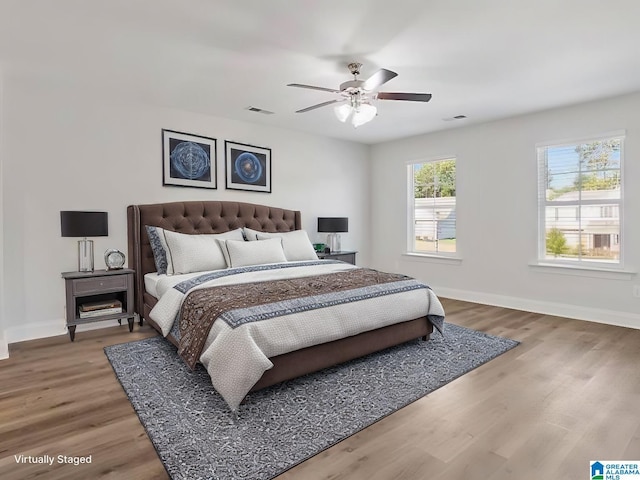 bedroom featuring visible vents, ceiling fan, baseboards, and wood finished floors