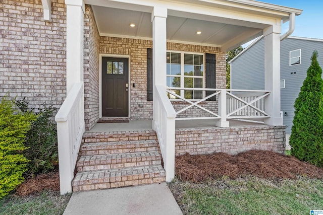 view of exterior entry featuring brick siding and a porch