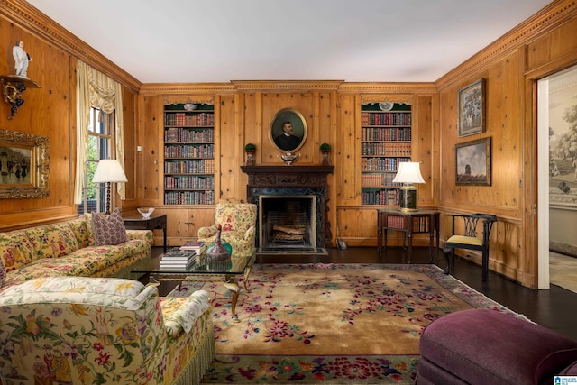 living room featuring hardwood / wood-style flooring, built in shelves, wooden walls, and ornamental molding