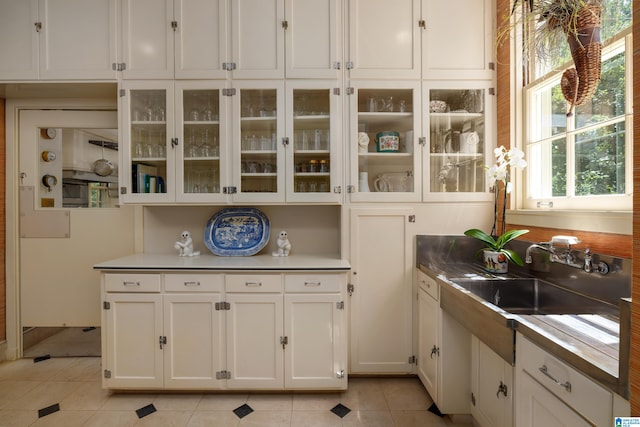 kitchen with light tile patterned flooring, sink, and white cabinets