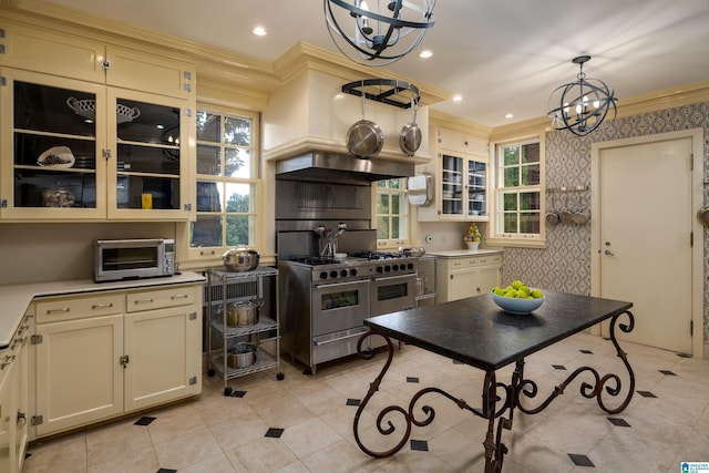 kitchen with double oven range, hanging light fixtures, light tile patterned floors, cream cabinets, and a notable chandelier