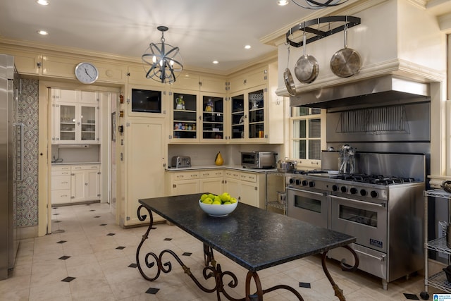 kitchen with light tile patterned flooring, a notable chandelier, cream cabinetry, range with two ovens, and ornamental molding