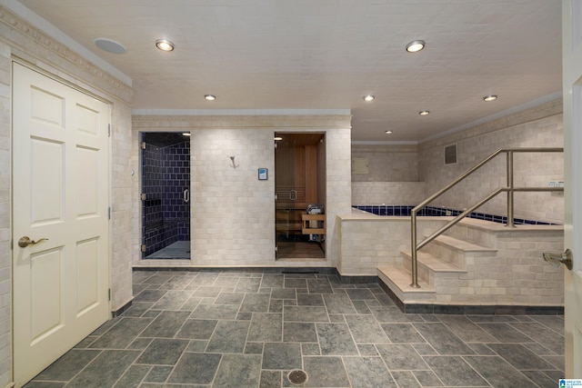 interior space featuring ornamental molding, dark tile patterned flooring, and tile walls