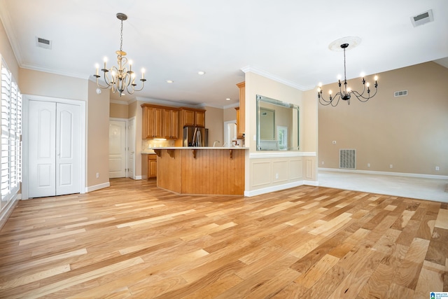 kitchen featuring an inviting chandelier, a breakfast bar area, stainless steel fridge, light hardwood / wood-style flooring, and kitchen peninsula