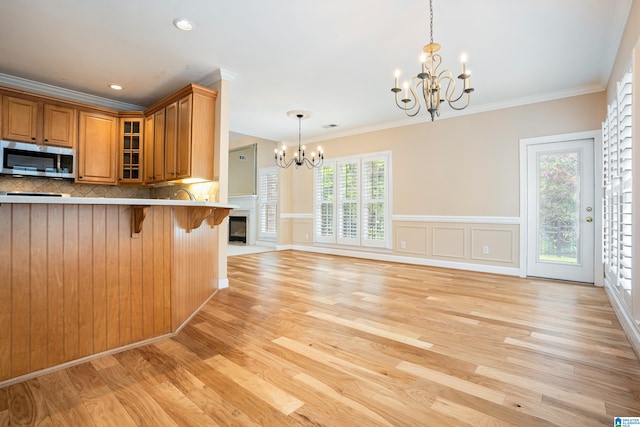 kitchen with decorative backsplash, light hardwood / wood-style floors, crown molding, and a breakfast bar