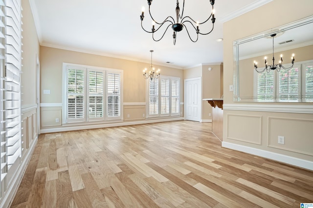 unfurnished living room featuring crown molding, light wood-type flooring, and a chandelier