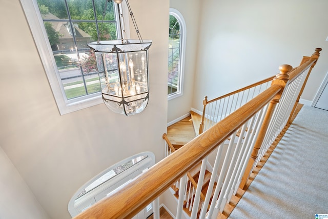 stairs with carpet flooring, a notable chandelier, and plenty of natural light