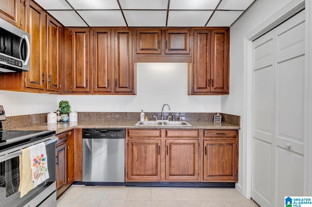 kitchen with sink, a drop ceiling, light tile patterned floors, and stainless steel appliances