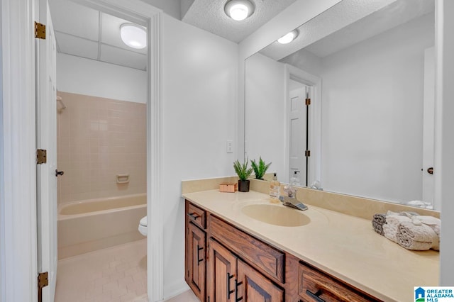 full bathroom featuring vanity, tile patterned floors, tiled shower / bath, toilet, and a textured ceiling