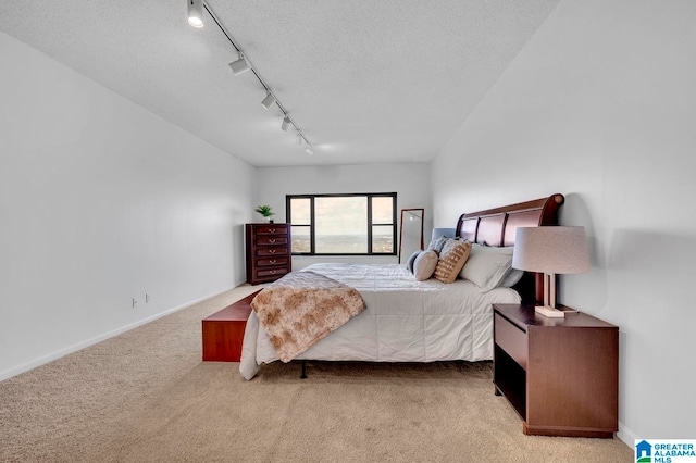 carpeted bedroom featuring a textured ceiling and track lighting