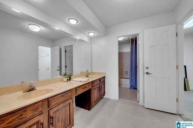 bathroom with tile patterned floors, double sink vanity, and a textured ceiling