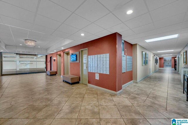 hallway featuring tile patterned floors and a drop ceiling