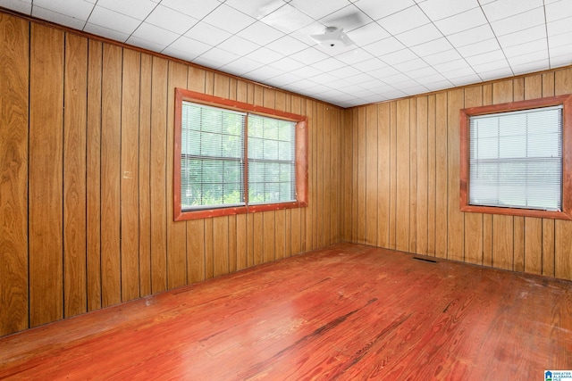 unfurnished room featuring wooden walls and hardwood / wood-style floors