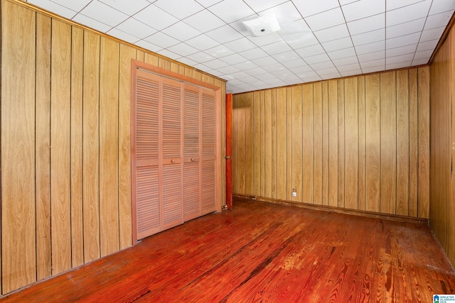 unfurnished bedroom featuring dark wood-type flooring, a closet, and wood walls