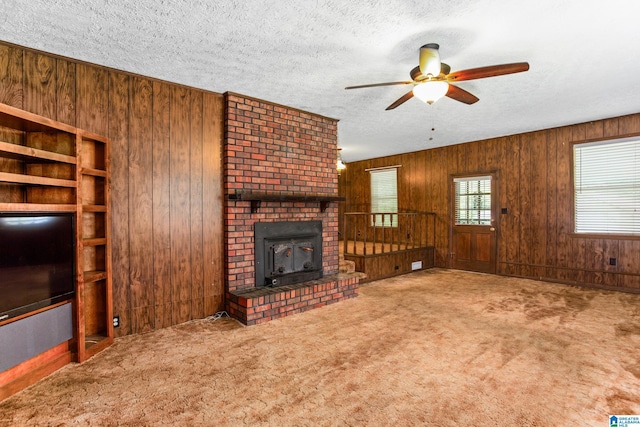 unfurnished living room with wooden walls, carpet flooring, and a textured ceiling