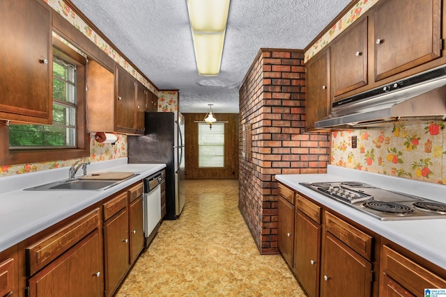 kitchen with pendant lighting, sink, a textured ceiling, and appliances with stainless steel finishes