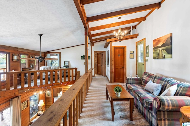 carpeted living room with a textured ceiling, a notable chandelier, and vaulted ceiling with beams